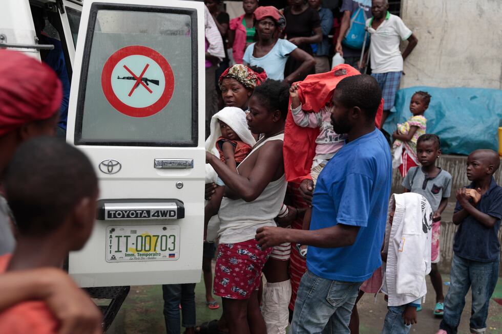 Displaced people who are living at a school due to gang violence line up with their children...